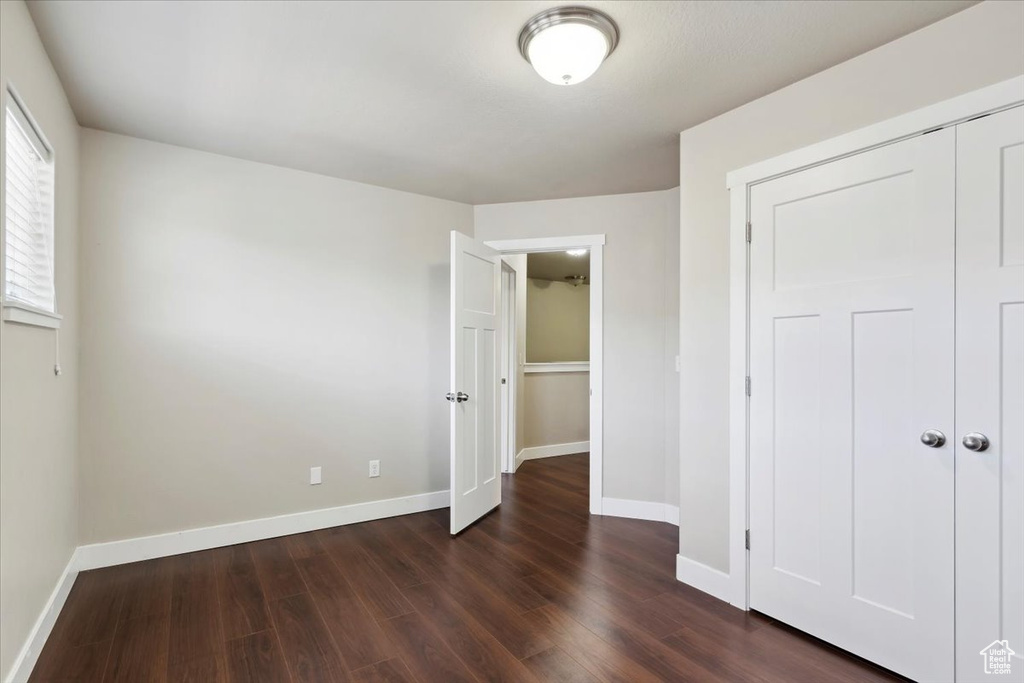 Unfurnished bedroom with dark wood finished floors, baseboards, and a closet