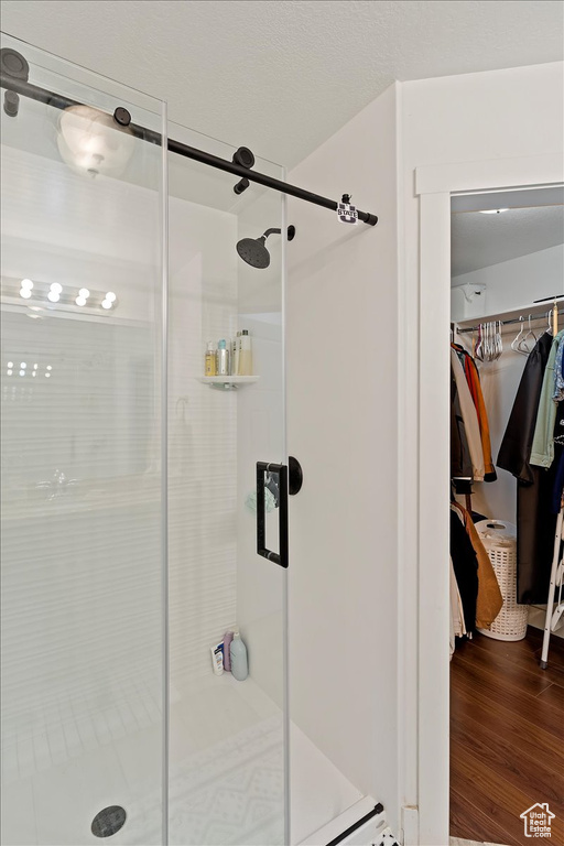 Full bathroom with wood finished floors, a stall shower, and a walk in closet