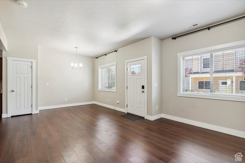 Foyer with a chandelier, baseboards, and dark wood-style floors