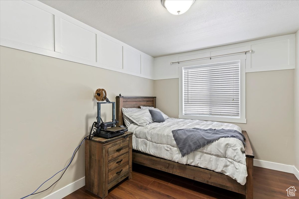 Bedroom with baseboards and dark wood-type flooring