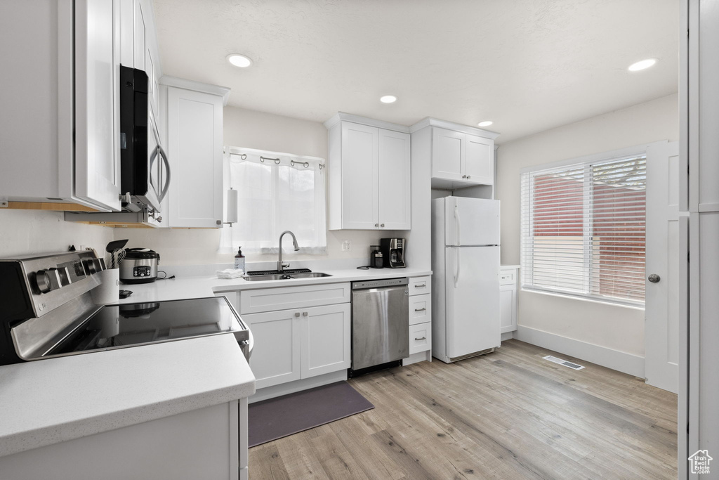 Kitchen with a sink, light wood-style floors, light countertops, stainless steel appliances, and visible vents