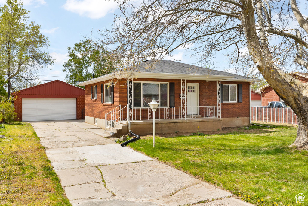 View of front of house featuring a porch, brick siding, an outbuilding, and a garage