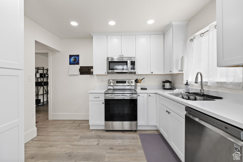 Kitchen with light countertops, stainless steel appliances, white cabinetry, and a sink