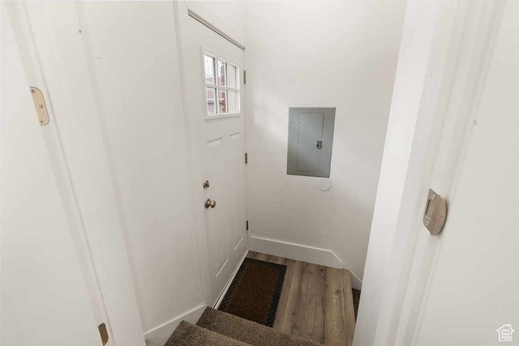 Staircase featuring baseboards, electric panel, and wood finished floors