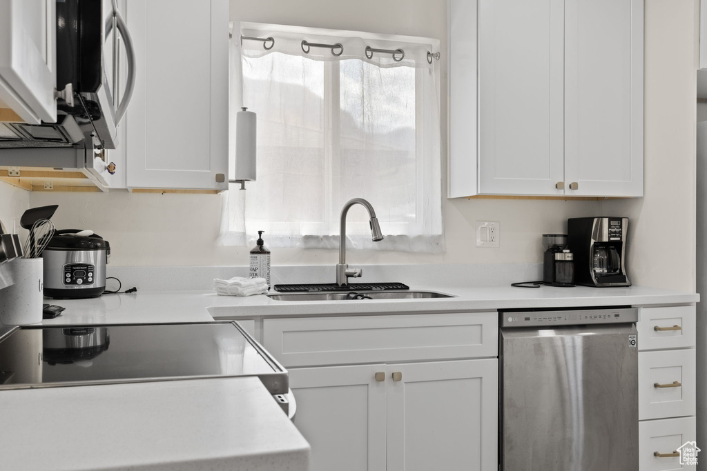 Kitchen featuring light countertops, white cabinetry, appliances with stainless steel finishes, and a sink
