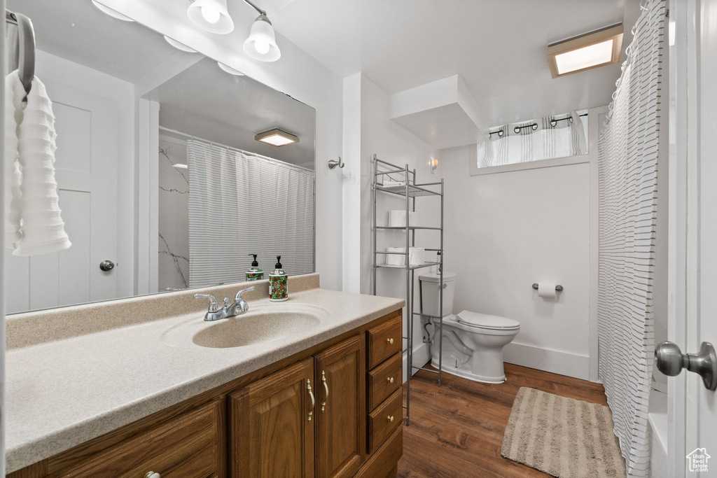 Full bathroom with vanity, toilet, a shower with shower curtain, baseboards, and wood finished floors