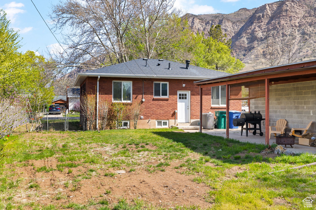 Back of property featuring brick siding, fence, cooling unit, a mountain view, and a patio