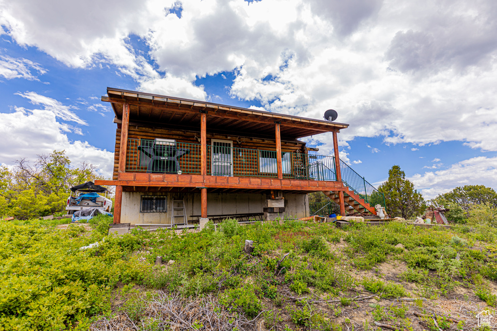 Rear view of property featuring a deck, log siding, and stairs