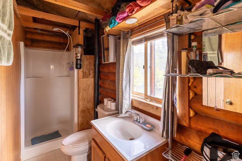 Bathroom featuring vanity, rustic walls, a stall shower, and toilet