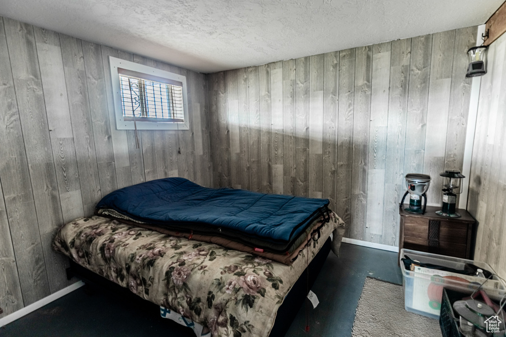 Bedroom with wood walls and a textured ceiling