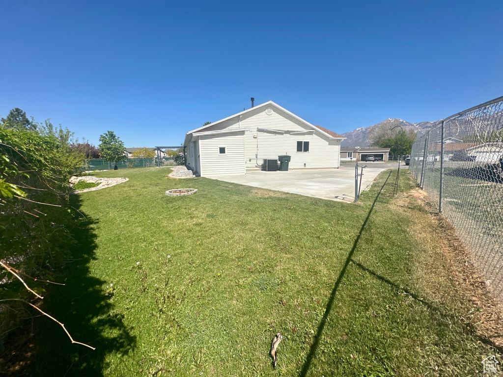 View of yard featuring a fenced backyard, a mountain view, central AC unit, a patio, and a fire pit