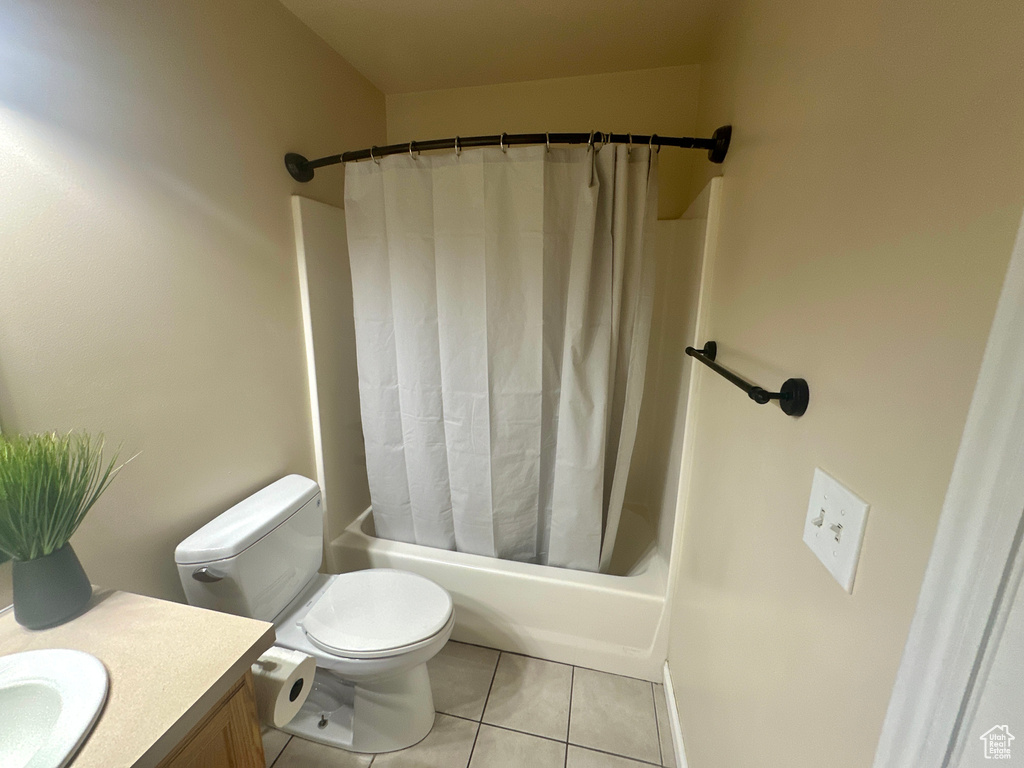 Bathroom featuring toilet, tile patterned floors, shower / bath combination with curtain, and vanity