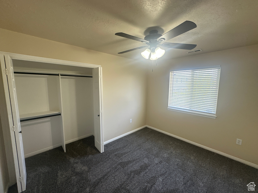 Unfurnished bedroom featuring visible vents, a closet, baseboards, dark colored carpet, and a textured ceiling