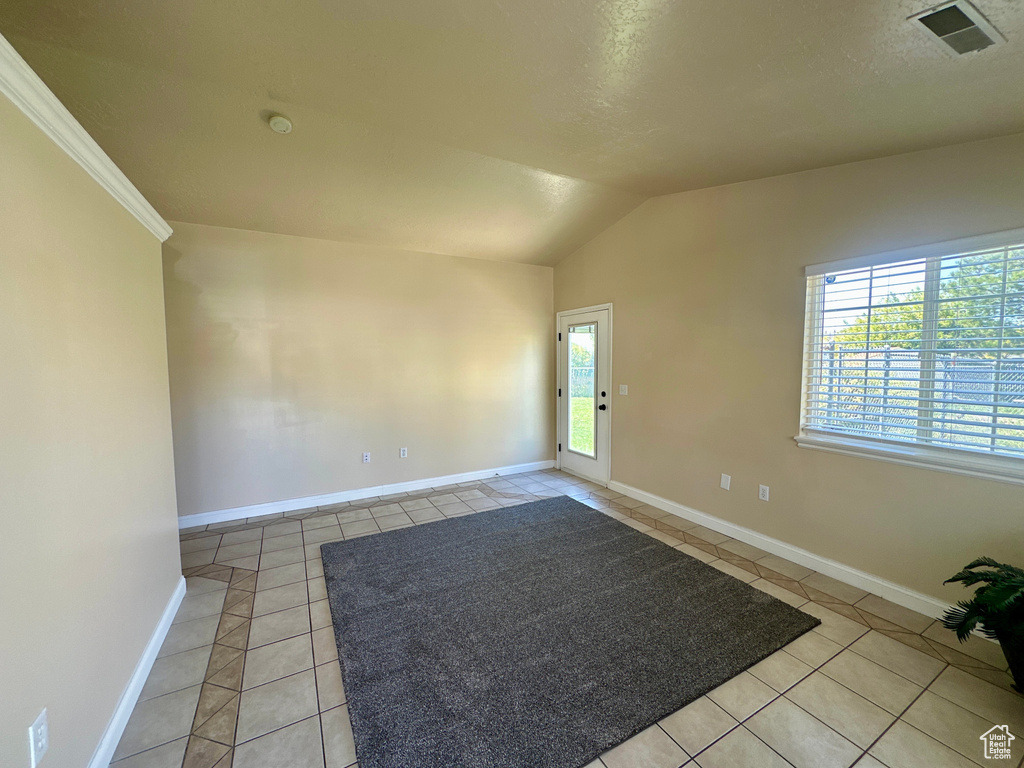 Unfurnished room featuring baseboards, visible vents, light tile patterned floors, and vaulted ceiling