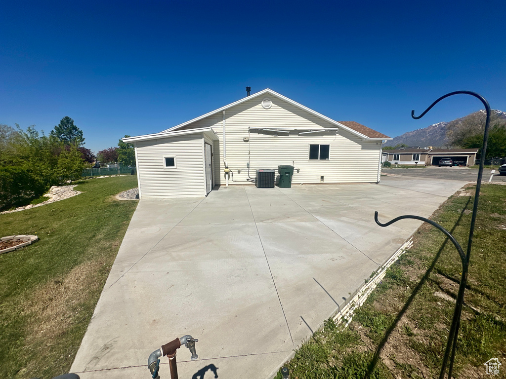 View of side of home featuring a yard, a patio, cooling unit, and a mountain view