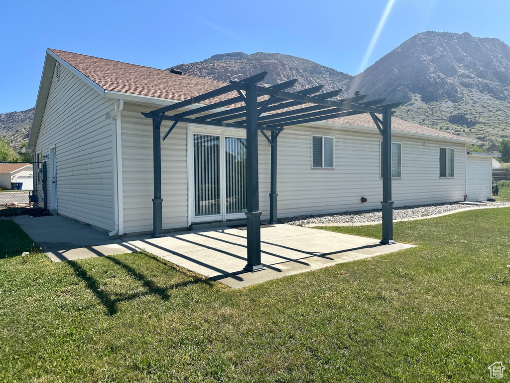 Rear view of house featuring a lawn, a pergola, a mountain view, and roof with shingles