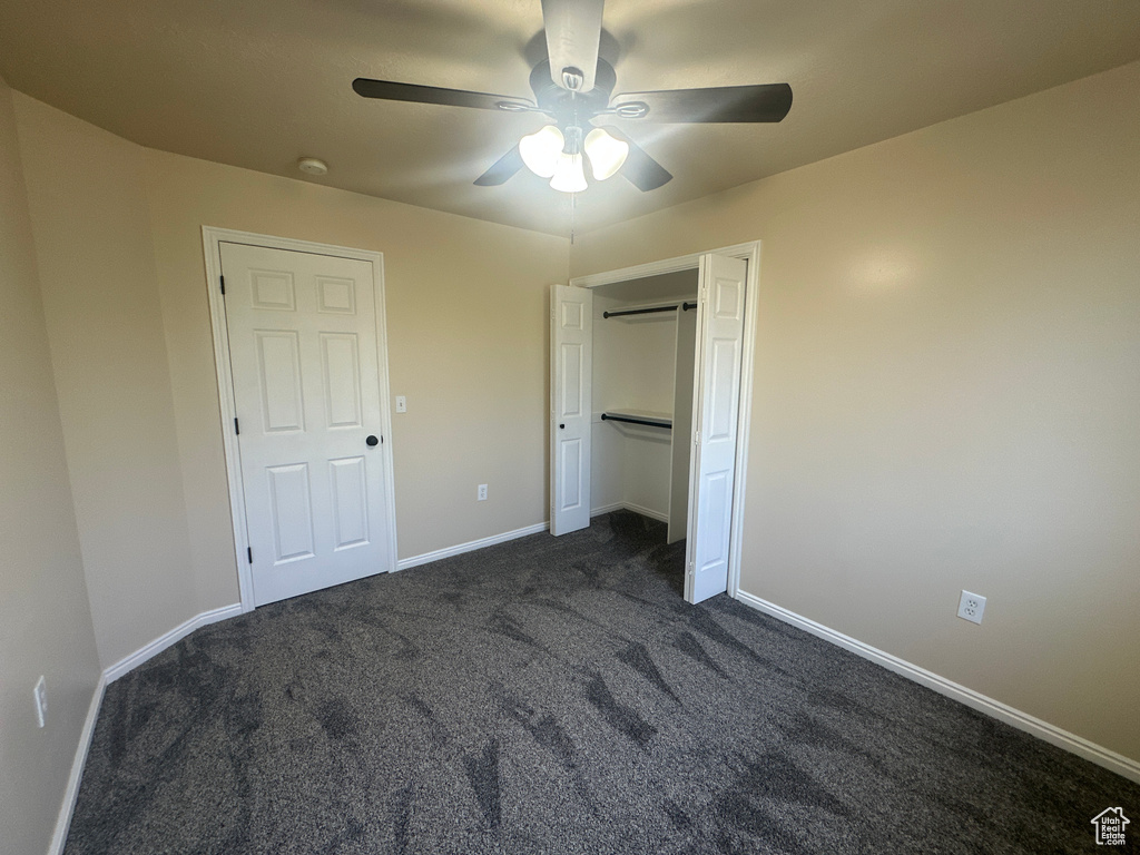 Unfurnished bedroom with baseboards, ceiling fan, a closet, and dark carpet