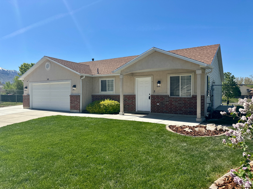 View of front of home featuring roof with shingles, fence, a garage, and brick siding