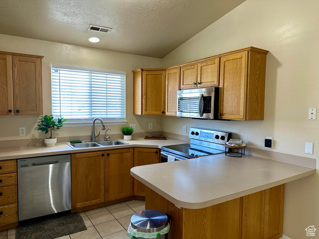Kitchen featuring a textured ceiling, visible vents, a sink, a peninsula, and stainless steel appliances