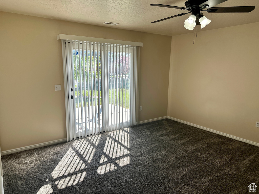 Carpeted spare room featuring a ceiling fan, a textured ceiling, visible vents, and baseboards