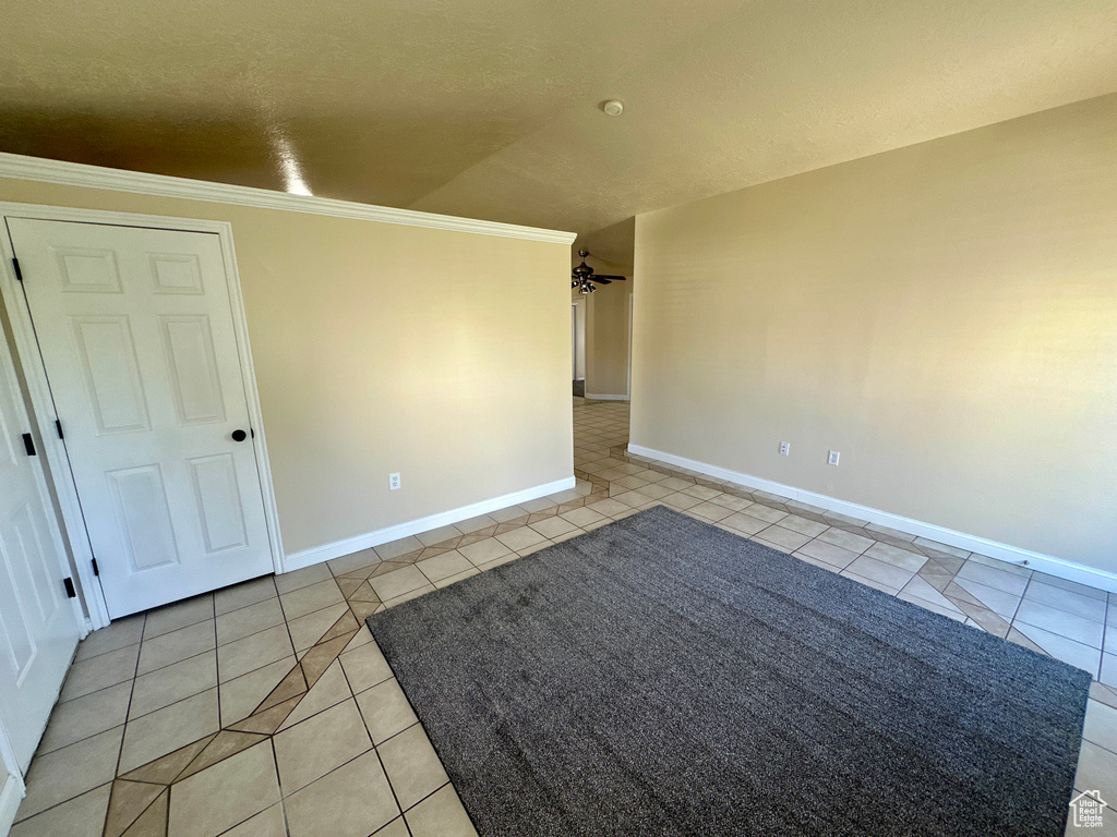 Spare room featuring baseboards, ceiling fan, ornamental molding, and light tile patterned floors
