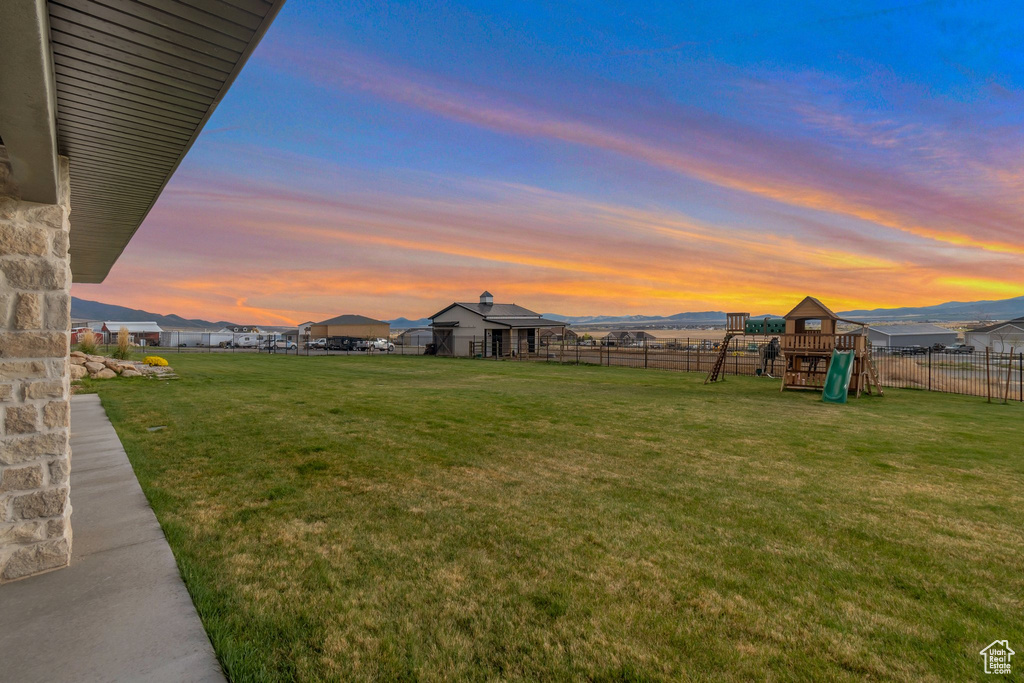 Yard at dusk with a playground and fence