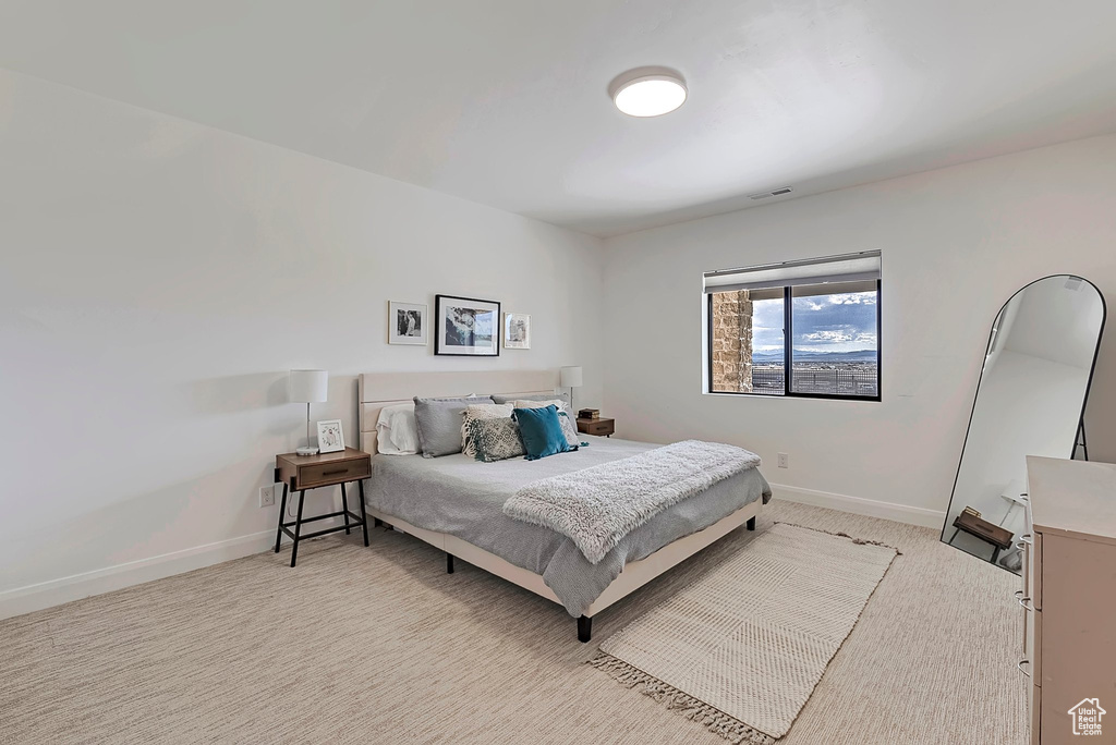 Bedroom with baseboards, visible vents, and light colored carpet