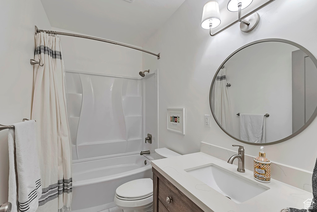 Bathroom featuring toilet, shower / bath combination with curtain, and vanity