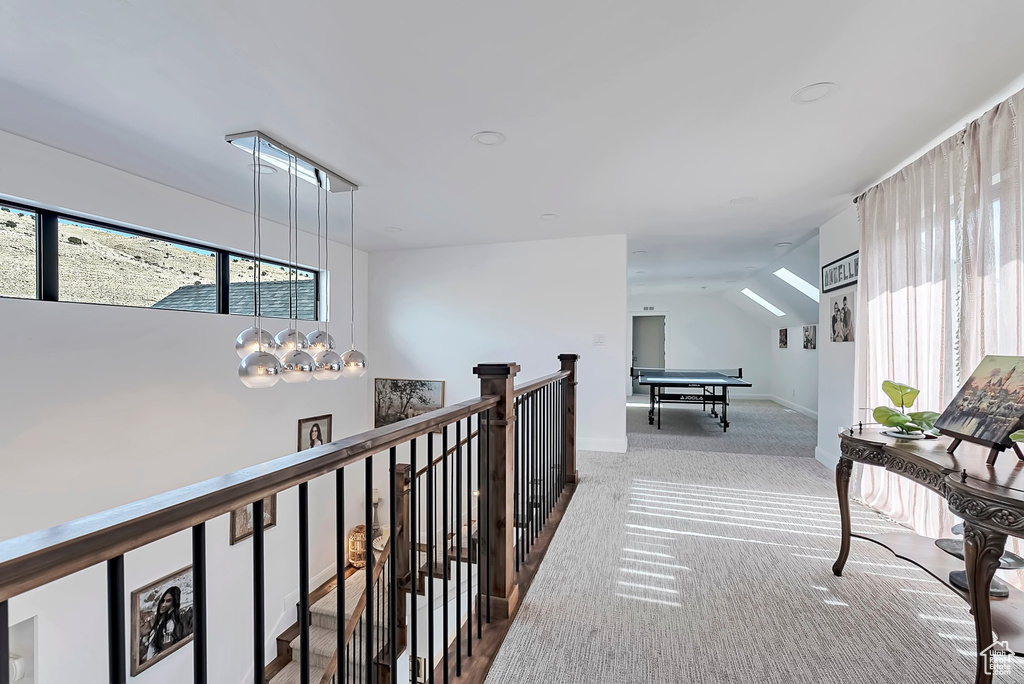 Hallway featuring carpet flooring, an upstairs landing, plenty of natural light, and vaulted ceiling