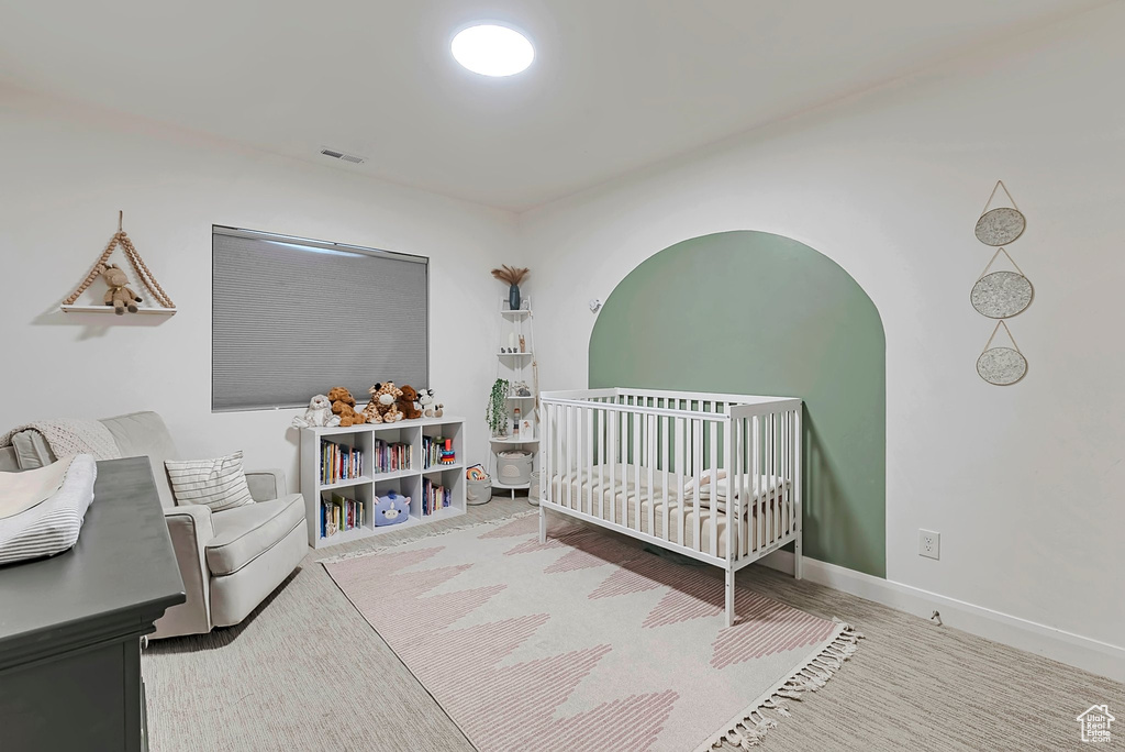 Bedroom with visible vents, baseboards, and a nursery area