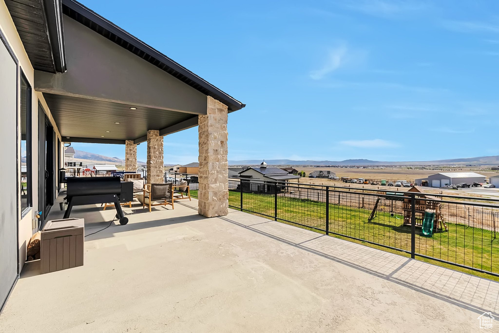 View of patio / terrace with fence, a mountain view, and playground community