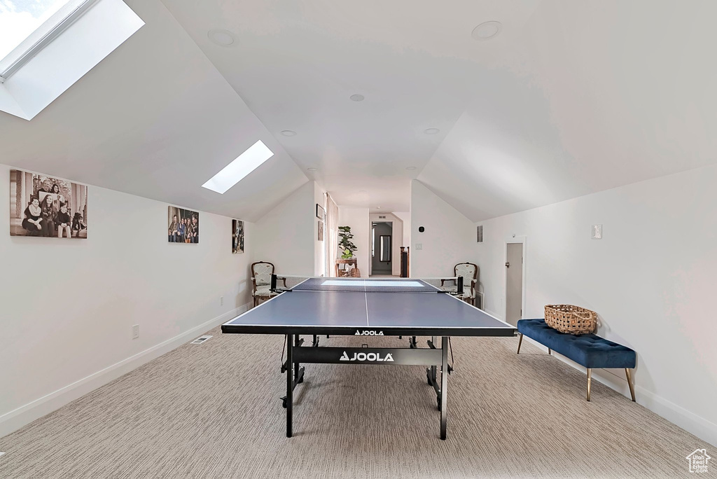 Game room with carpet flooring, baseboards, and lofted ceiling with skylight