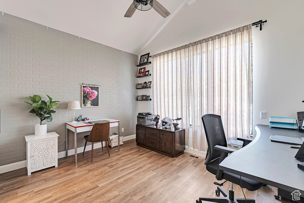 Office area featuring ceiling fan, brick wall, baseboards, light wood-type flooring, and visible vents