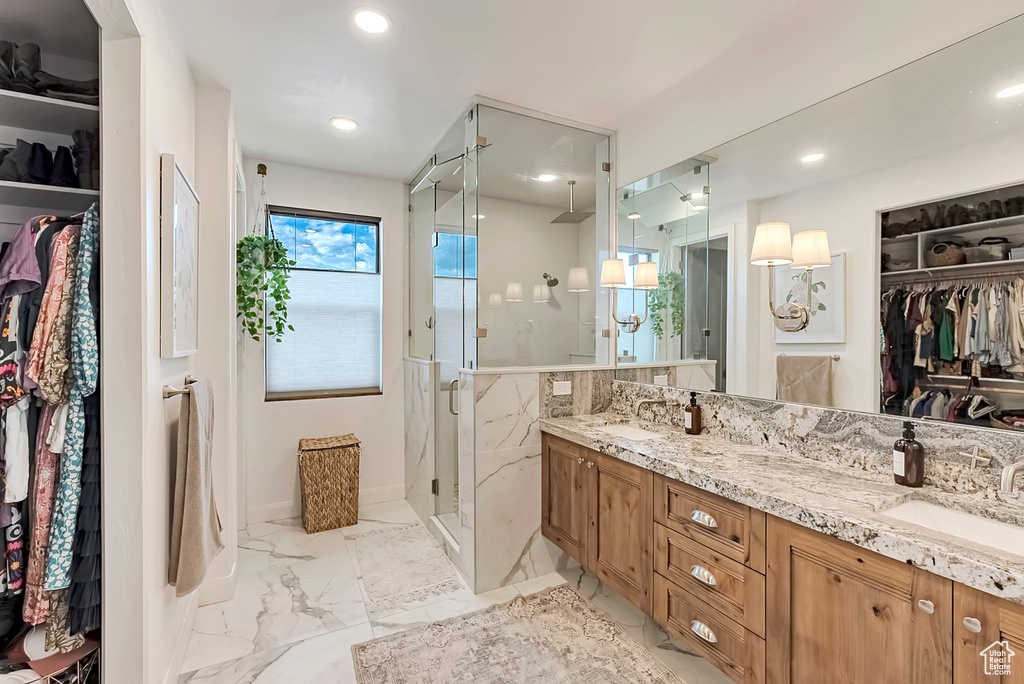 Full bath featuring a sink, a shower stall, double vanity, and marble finish floor