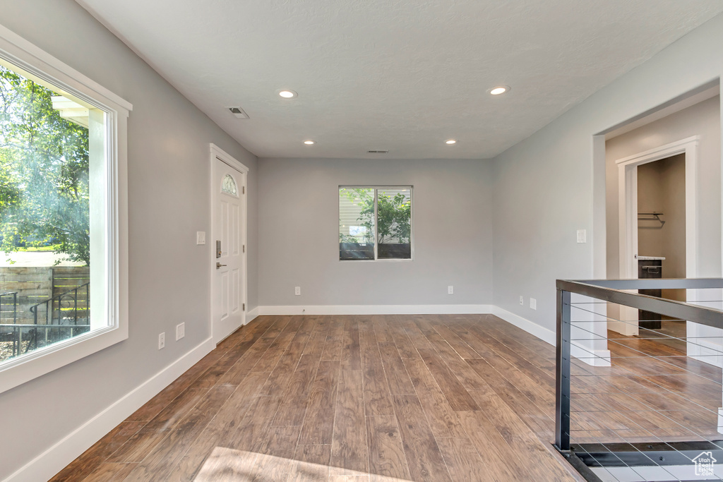 Empty room featuring dark wood-style flooring, baseboards, recessed lighting, and visible vents