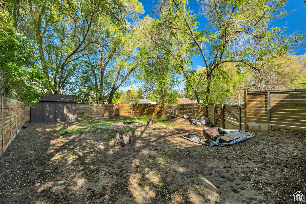 View of yard featuring an outdoor structure, a fenced backyard, and a storage shed