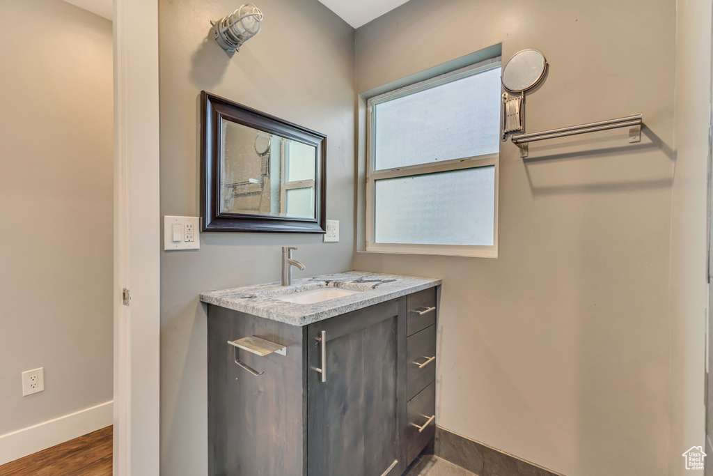 Bathroom featuring baseboards, vanity, and wood finished floors