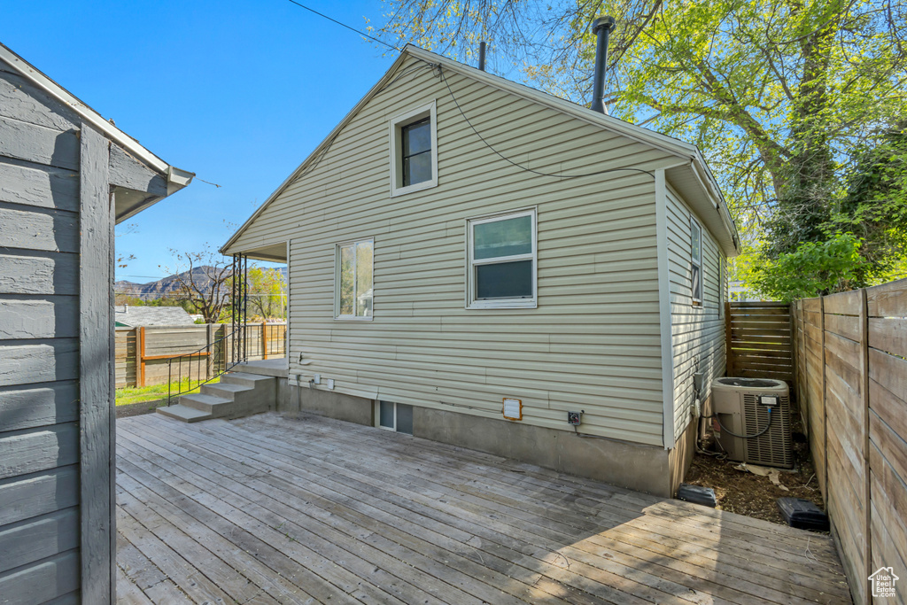 Rear view of property featuring central AC unit, a fenced backyard, and a deck