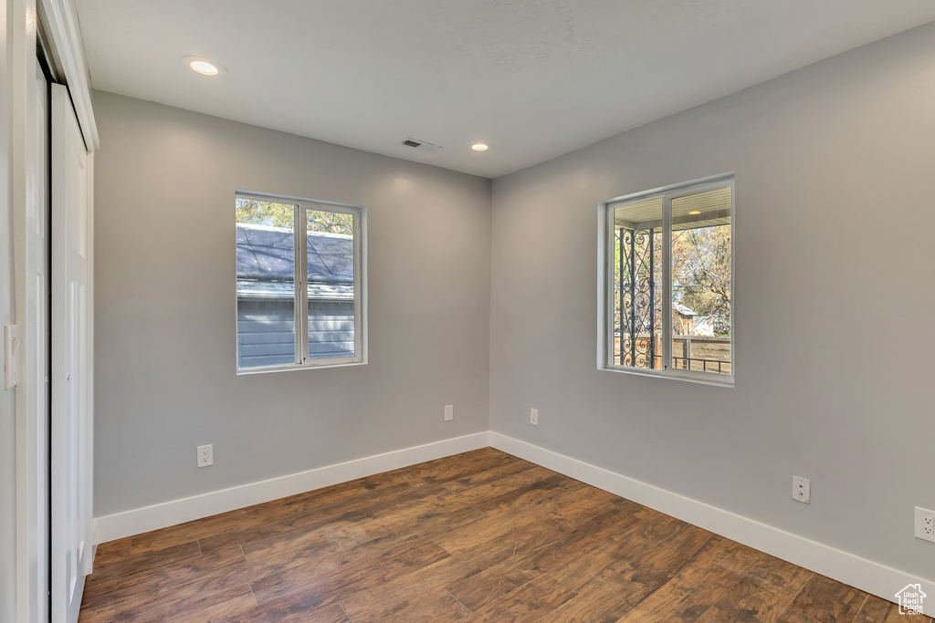 Unfurnished room featuring dark wood-style flooring, recessed lighting, baseboards, and visible vents