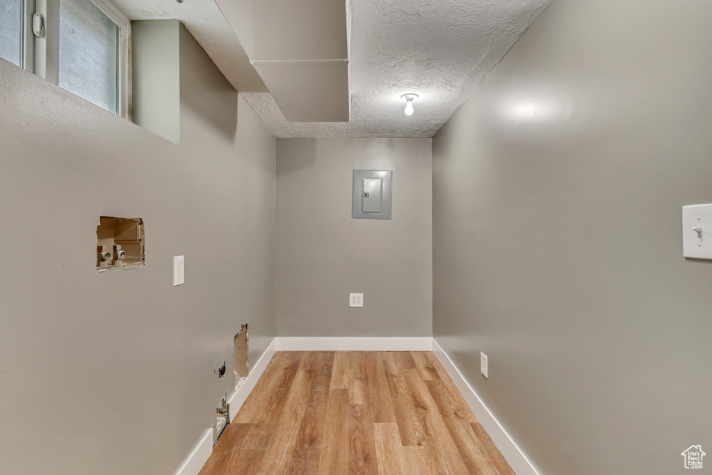 Clothes washing area featuring washer hookup, electric panel, laundry area, baseboards, and light wood-style floors