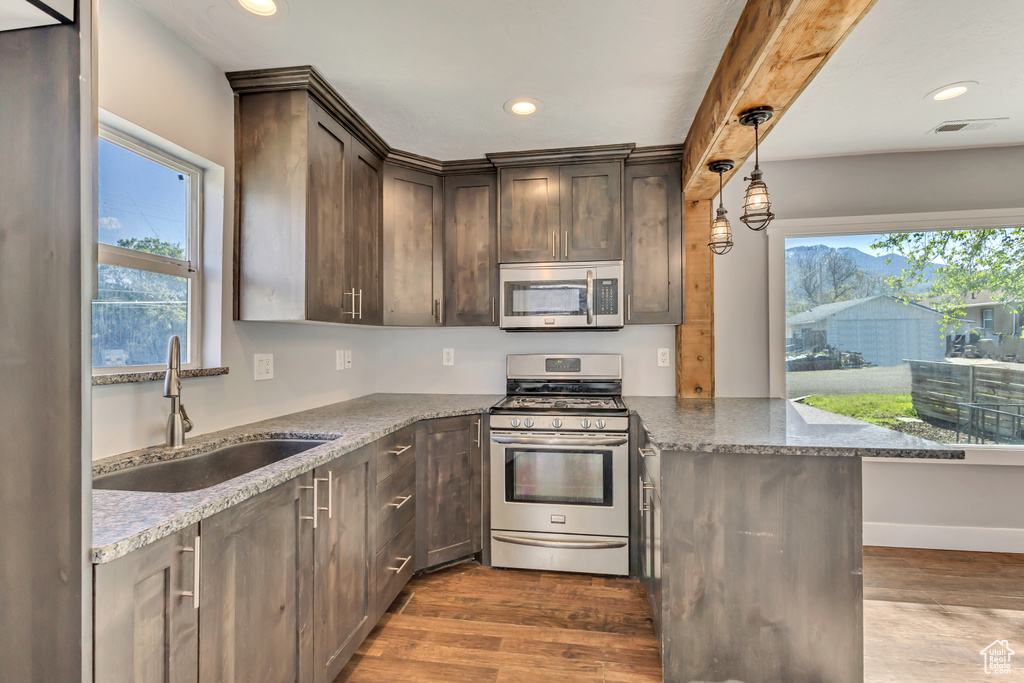 Kitchen with a peninsula, dark brown cabinets, recessed lighting, a sink, and stainless steel appliances