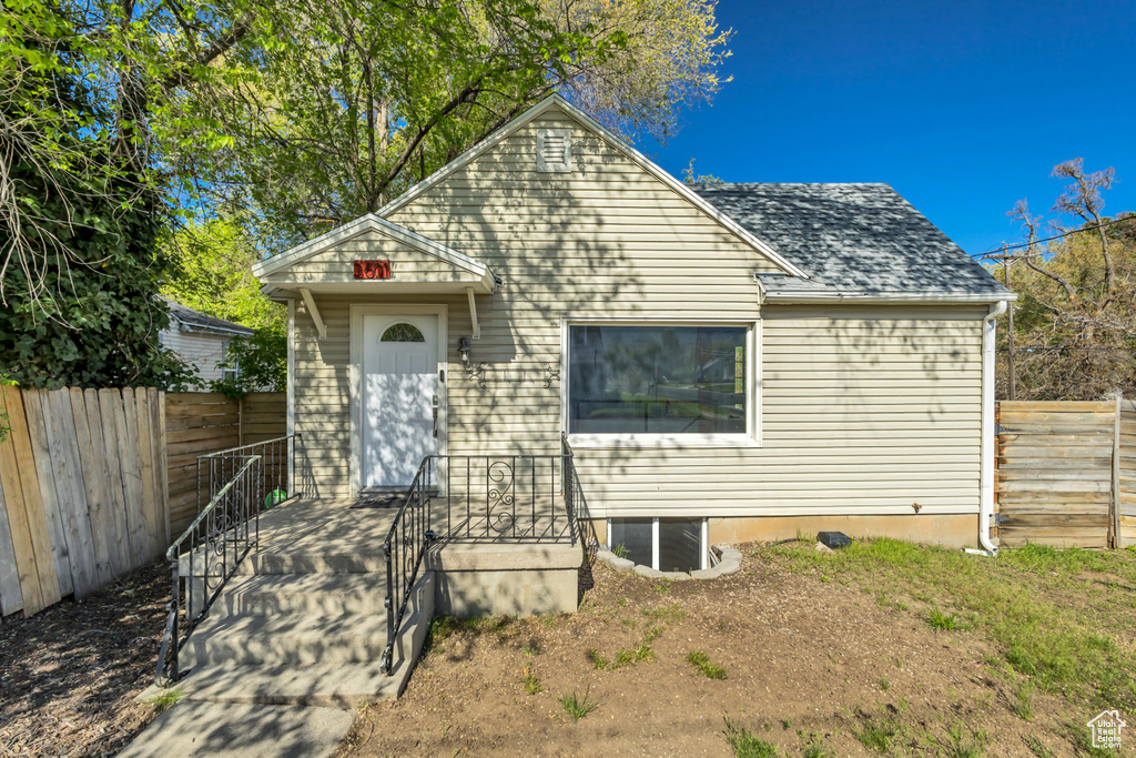 View of front of house featuring fence and a shingled roof
