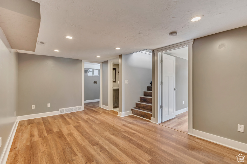 Finished basement featuring stairs, recessed lighting, visible vents, and light wood finished floors