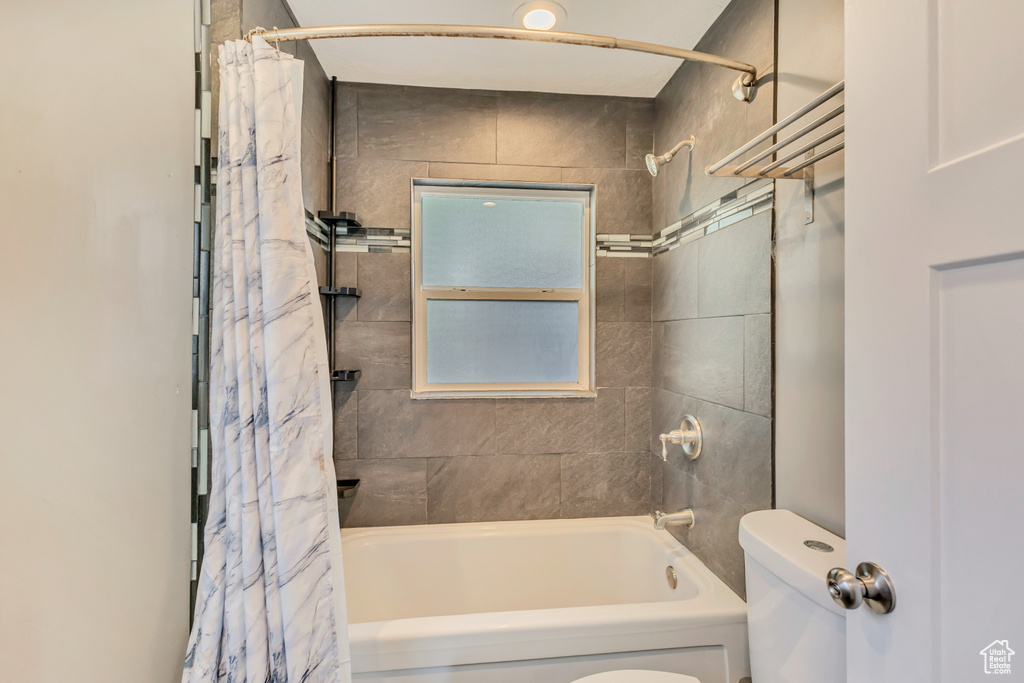 Bathroom with toilet and shower / bath combination with curtain