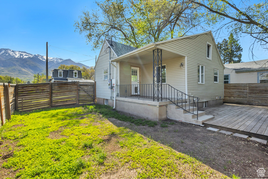 Bungalow with a fenced backyard, covered porch, a deck with mountain view, and roof with shingles