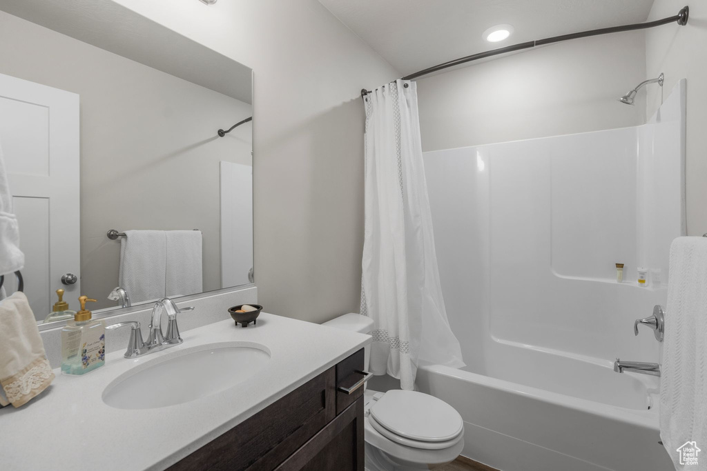 Bathroom with vanity, shower / bath combo, and toilet