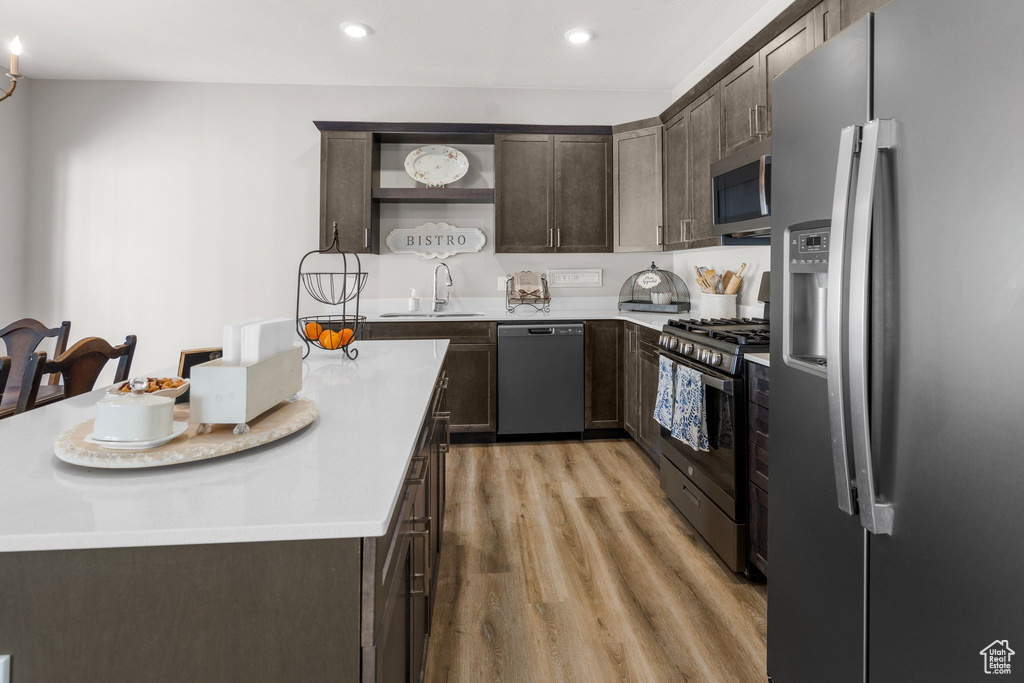 Kitchen with light wood-style floors, light countertops, appliances with stainless steel finishes, and dark brown cabinetry