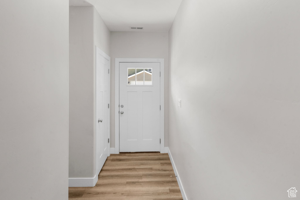 Doorway with baseboards, visible vents, and light wood finished floors