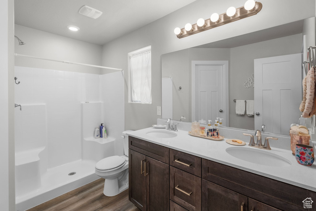 Full bathroom featuring toilet, a sink, a shower, and wood finished floors