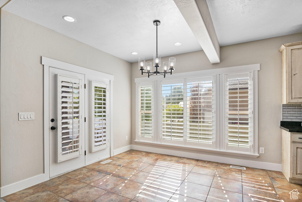 Unfurnished dining area featuring an inviting chandelier, recessed lighting, baseboards, beamed ceiling, and visible vents